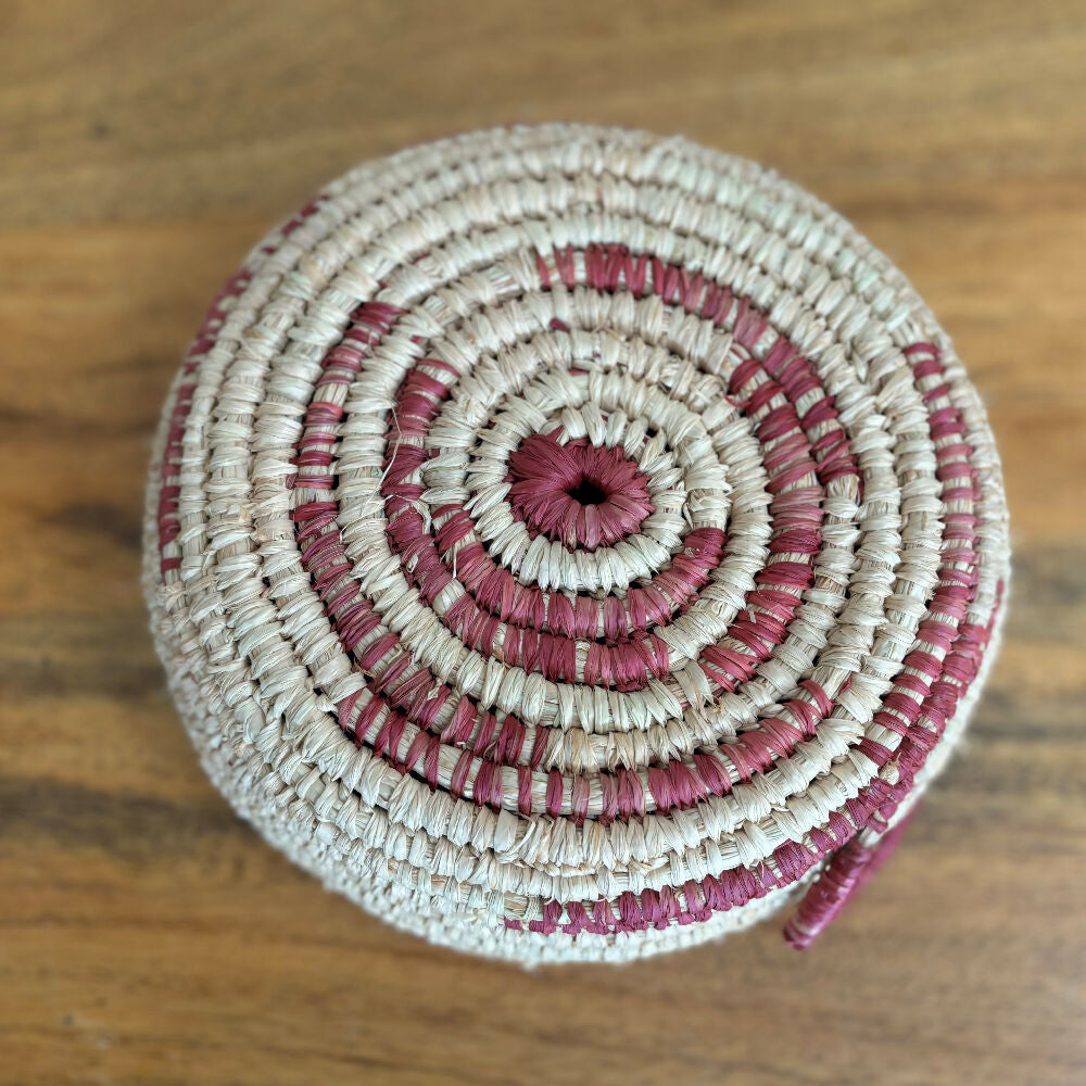 Handcrafted raffia bowl with red accents.