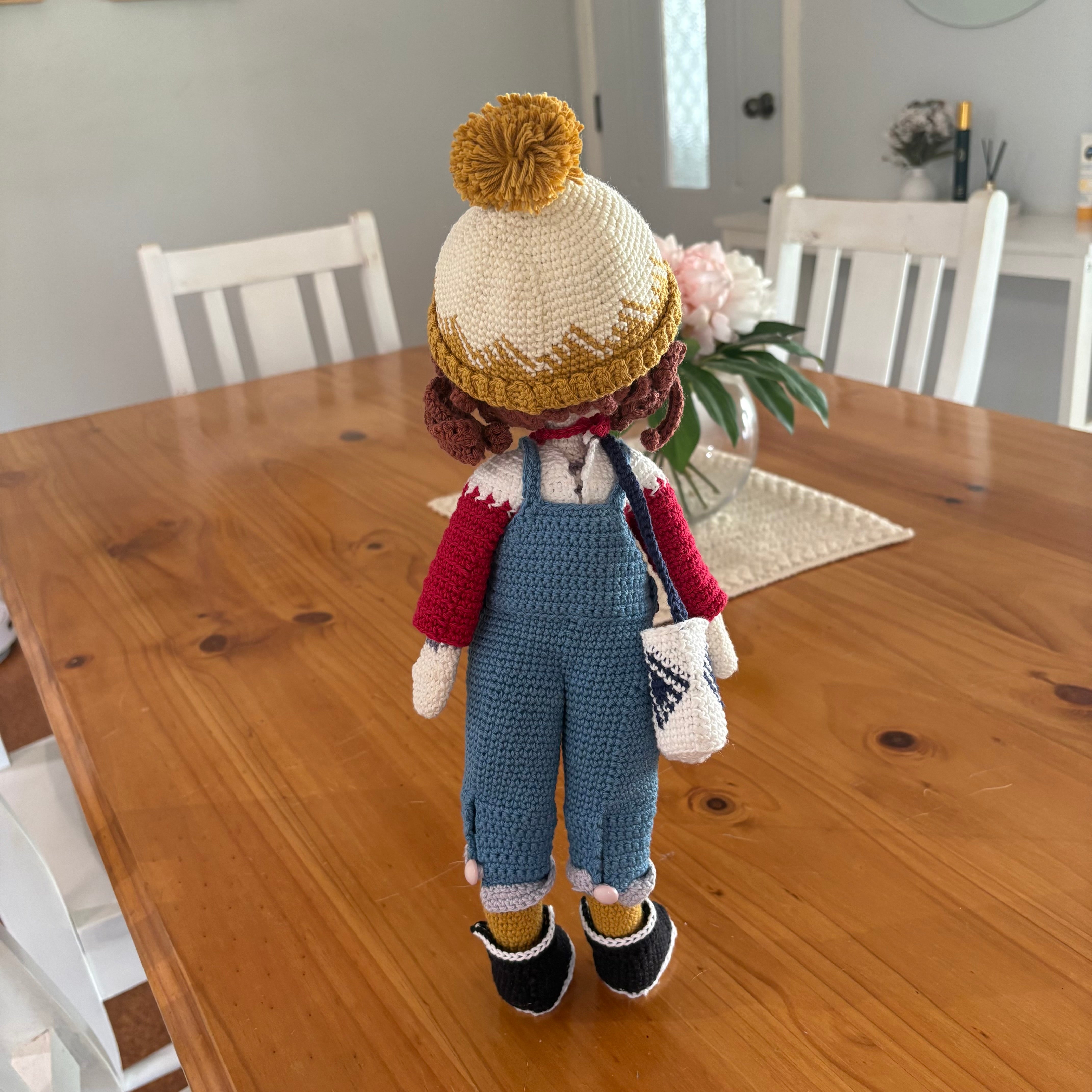 Crochet doll in overalls and beanie.
