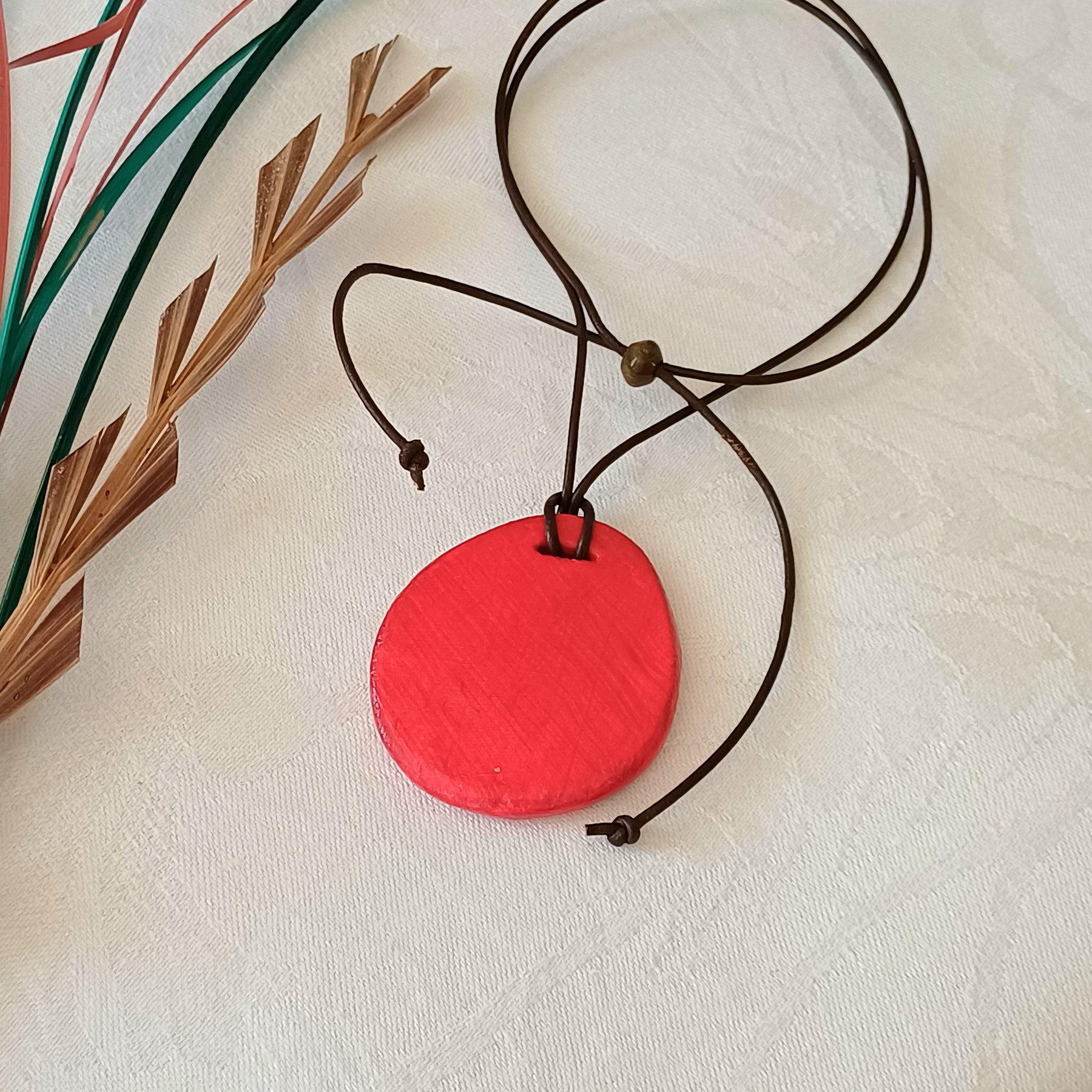 Hand-painted natural clay pendant with palm fibre heart