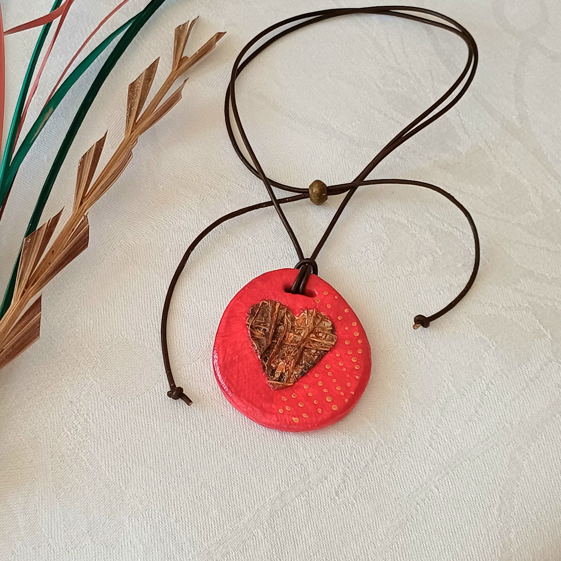Hand-painted natural clay pendant with palm fibre heart