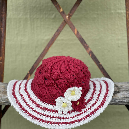 Cherry red spiral sun hat with daisy trim.