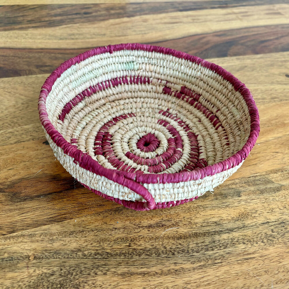 Handcrafted raffia bowl with red accents.