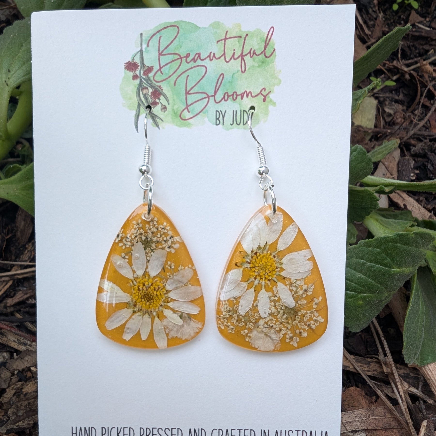 Real daisies in resin, mustard background