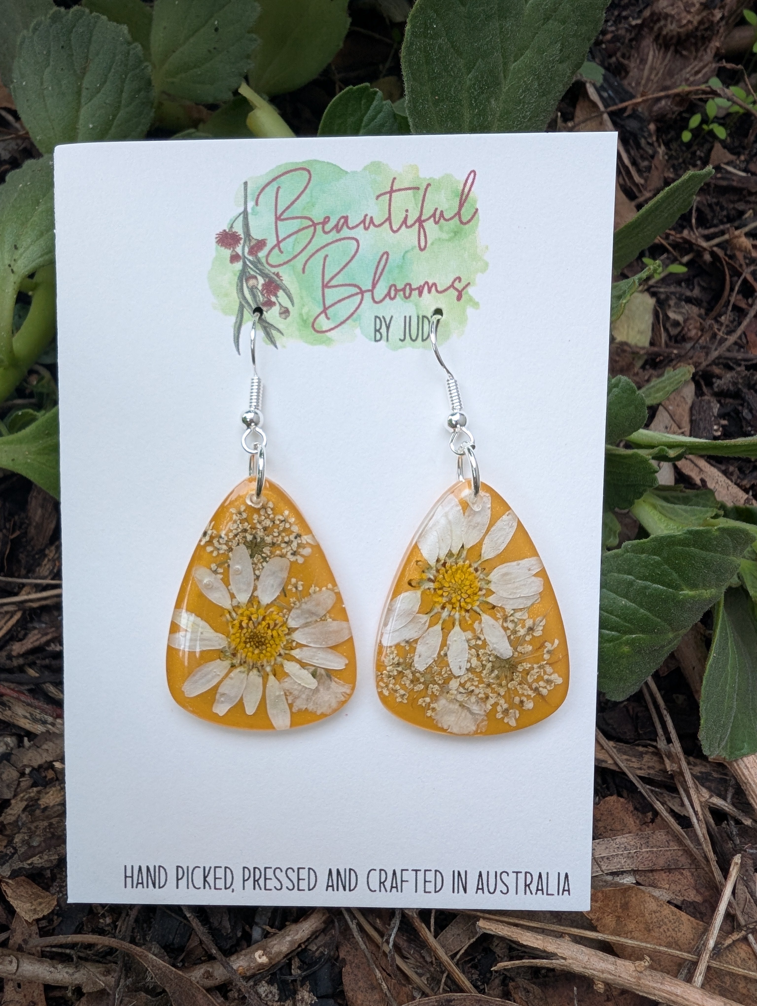Real daisies in resin, mustard background