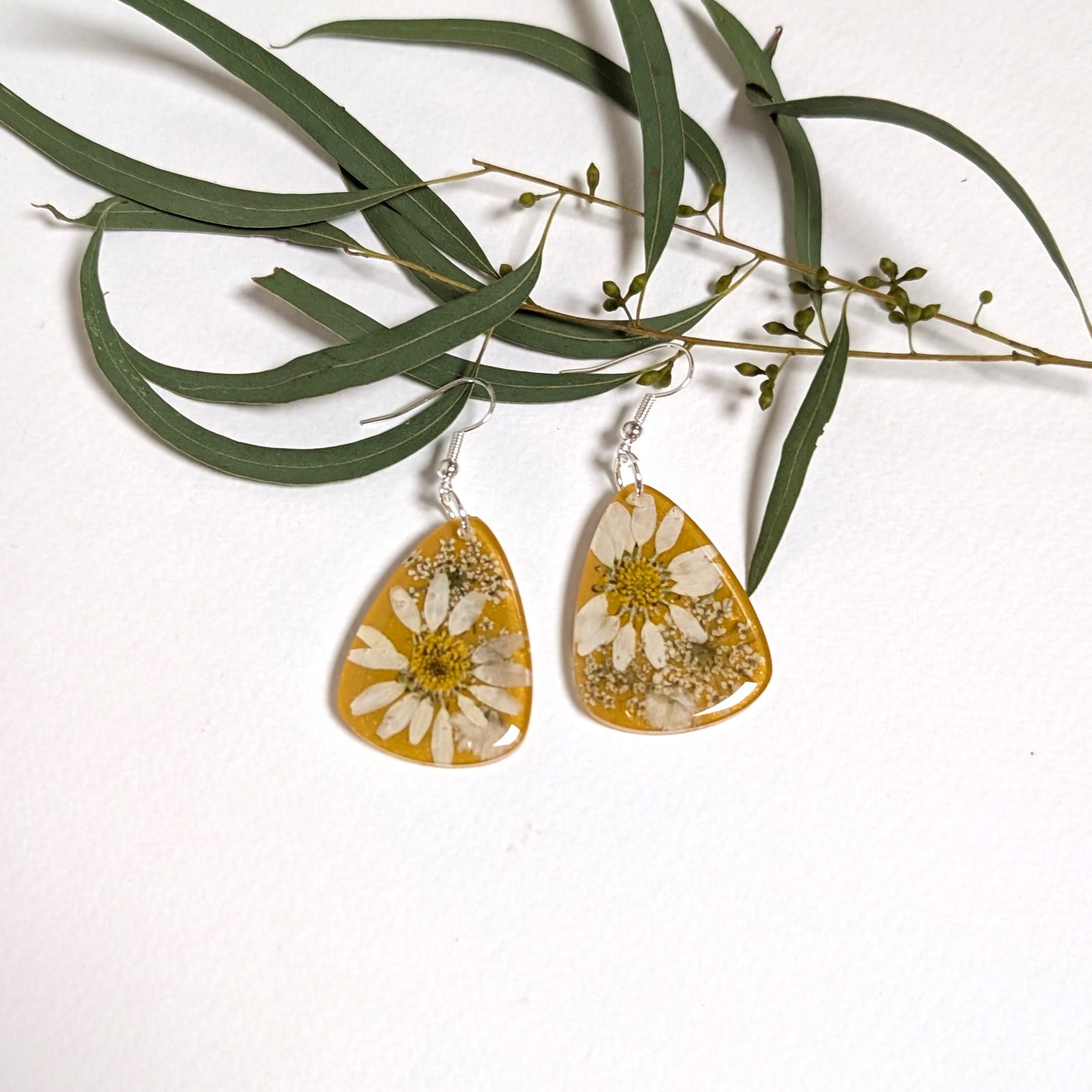 Real daisies in resin, mustard background
