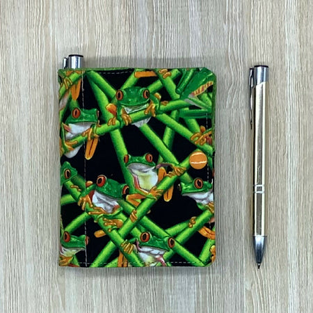 Green Frogs refillable fabric pocket notepad cover with snap closure. Incl. book and pen.