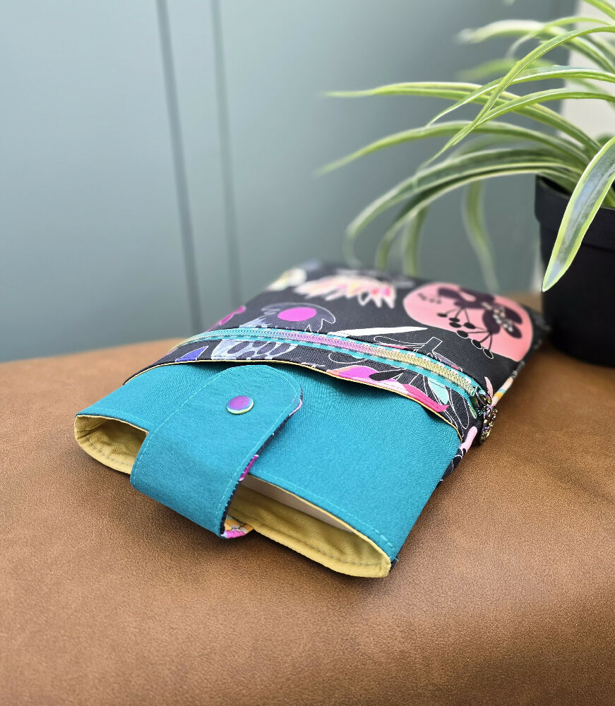 Book sleeve. Teal with native plants in rainbow colours.