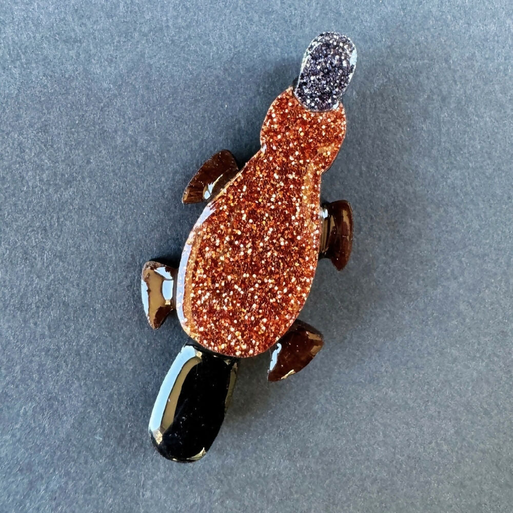 Australian-handmade-platypus-brooch-wood-glitter-resin-on-grey-background-square