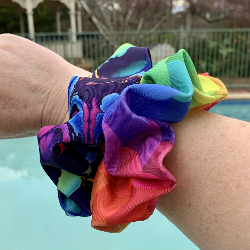 Rainbow Art & Mermaid Rainbow Swim Scrunchies on my arm with pool in background