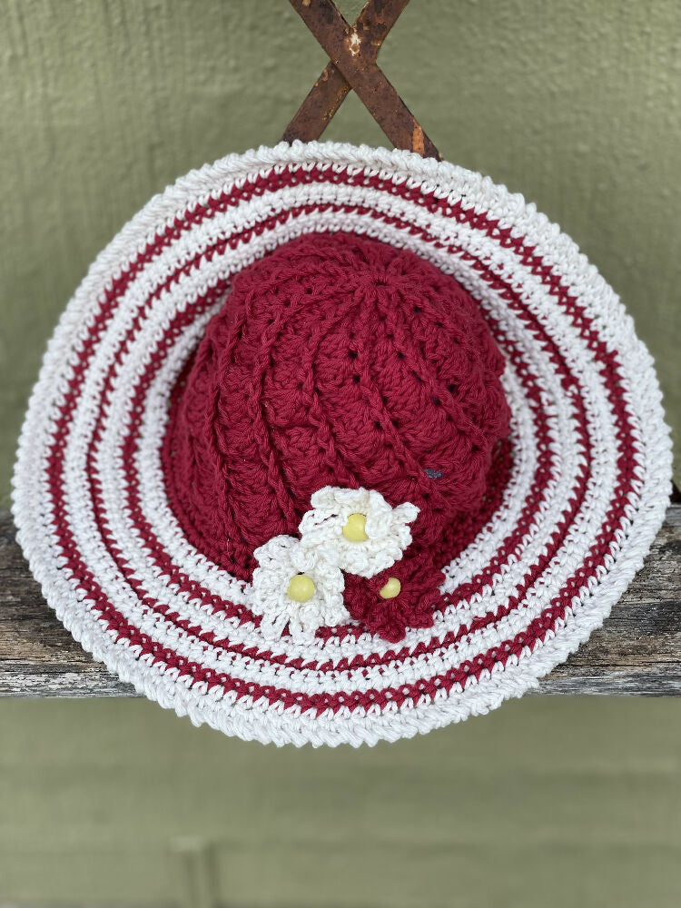 Cherry red spiral sun hat with daisy trim.