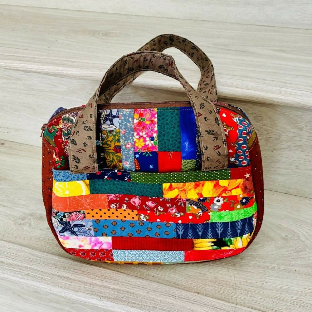 Compact curved gusseted patchwork handbag