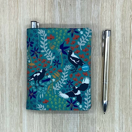 Magpie refillable fabric pocket notepad cover with snap closure. Incl. book and pen.