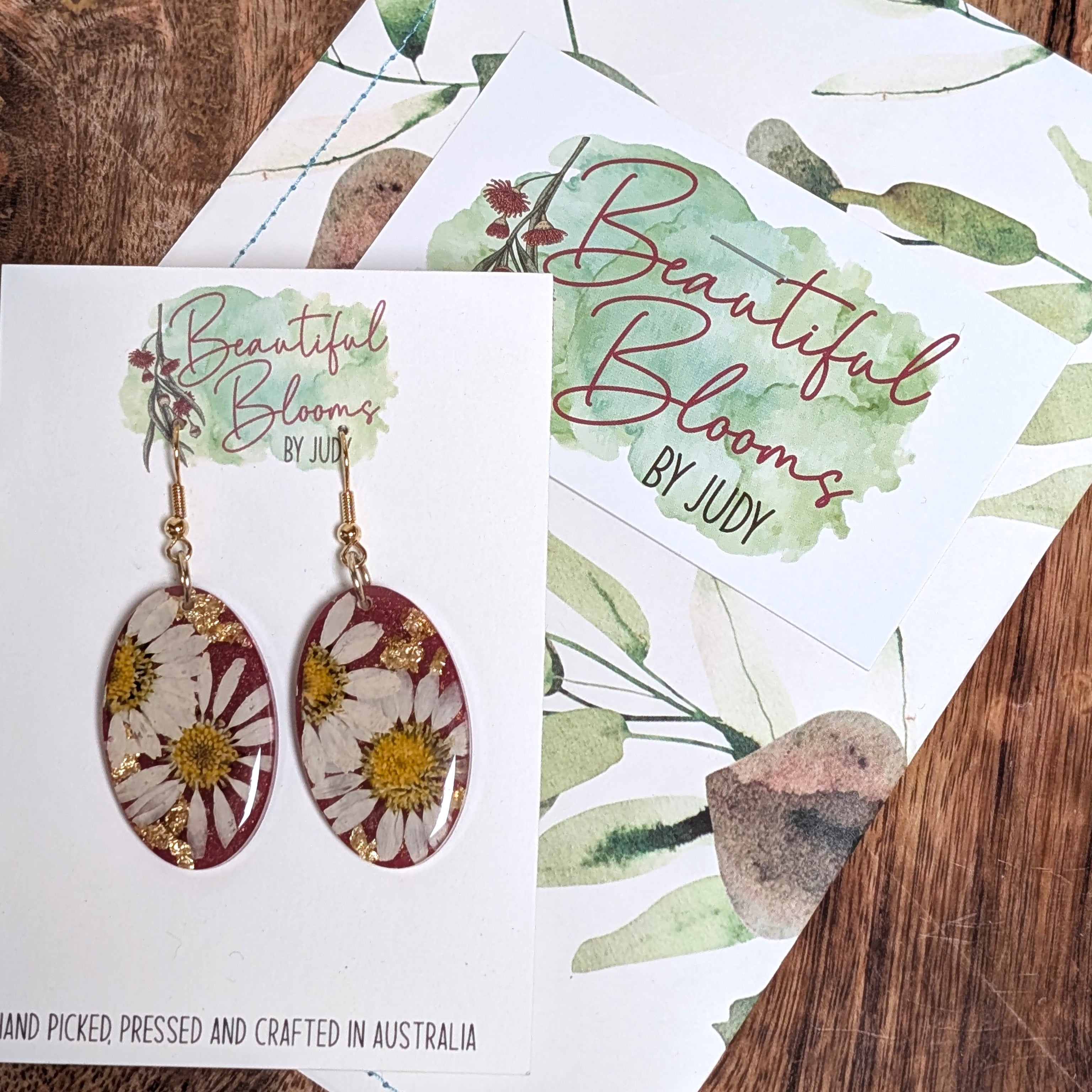 Real daisy earrings with merlot background
