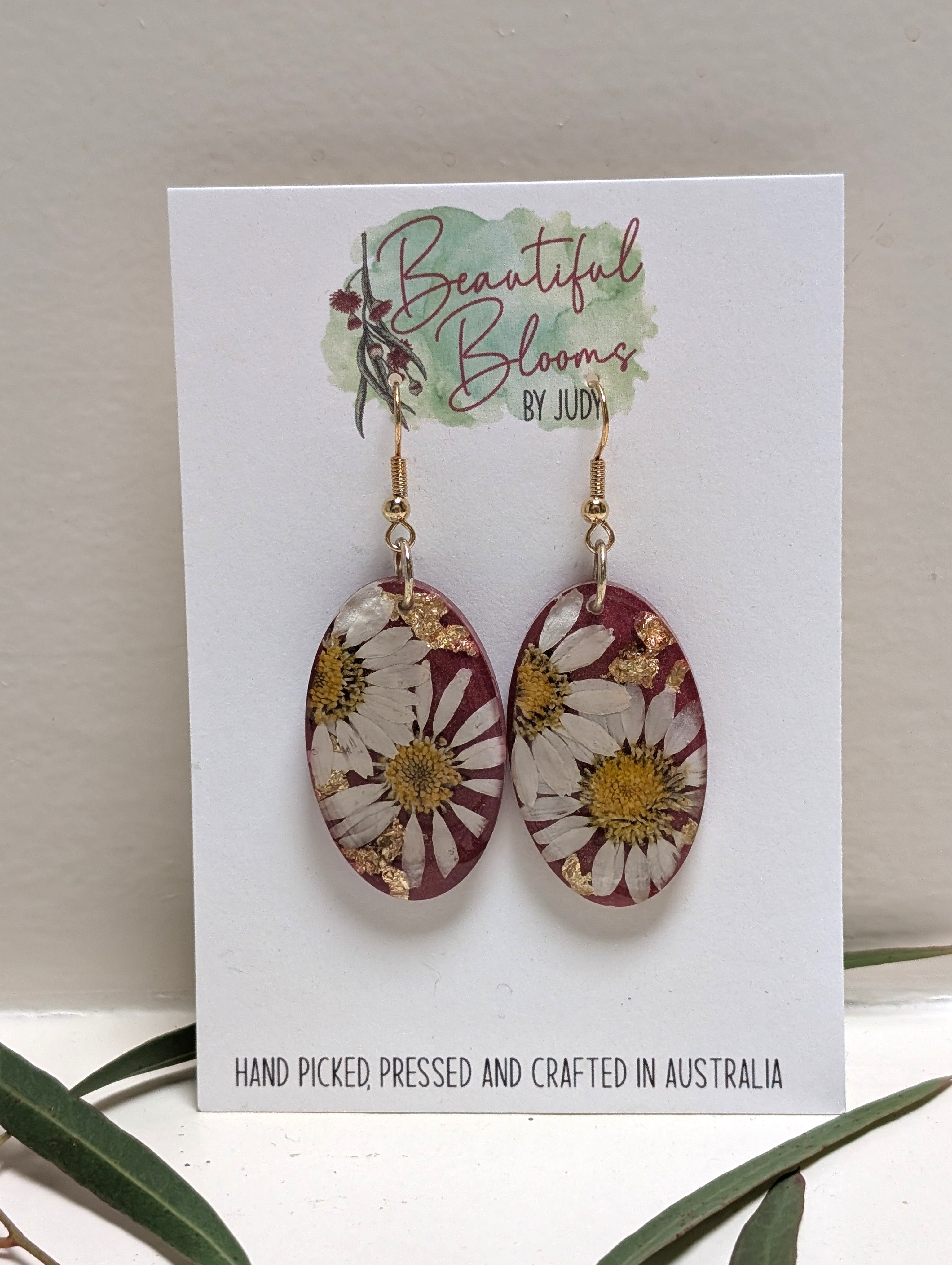 Real daisy earrings with merlot background