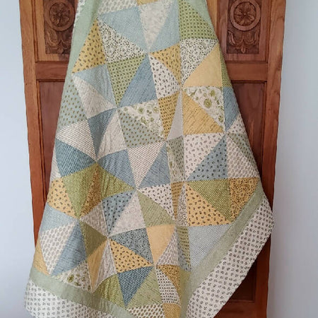 Lap quilt in soft blue, yellow, and green.