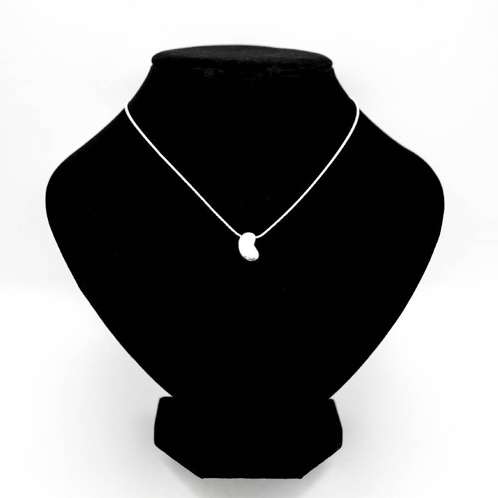 Image of a handmade shiny sterling silver bean pendant by Purplefish Designs Jewellery on a sterling silver snake chain necklace. The pendant is displayed on a black velvet neck bust to give an indication of size and scale.