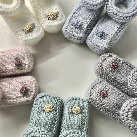 Hand-knitted baby booties with hand-embroidered rosebuds