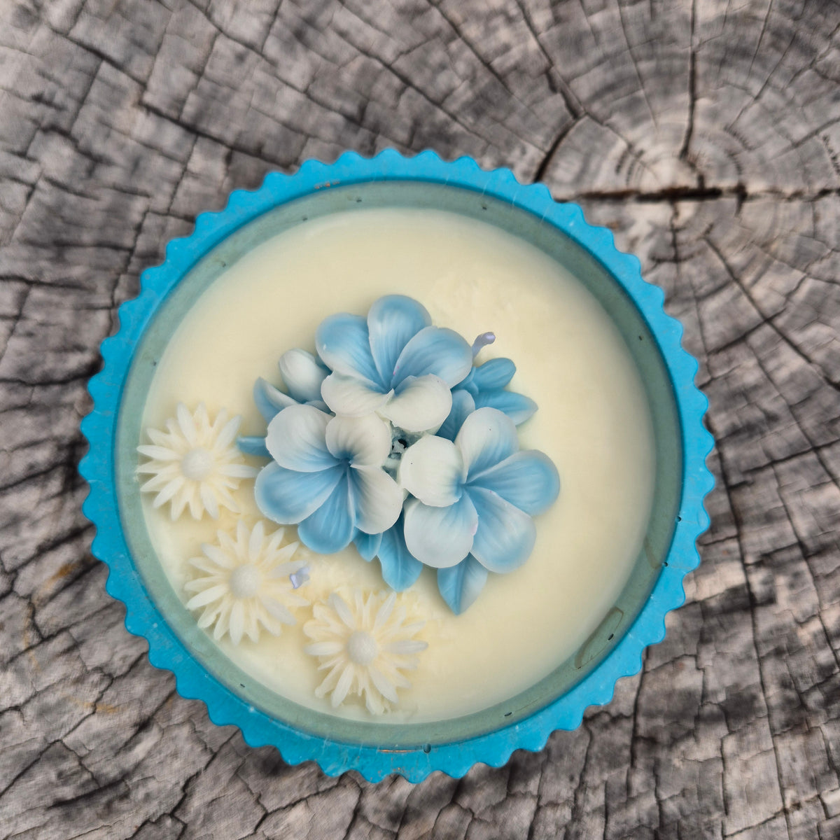 Round blue and gold concrete bowl candle with frangipani flower