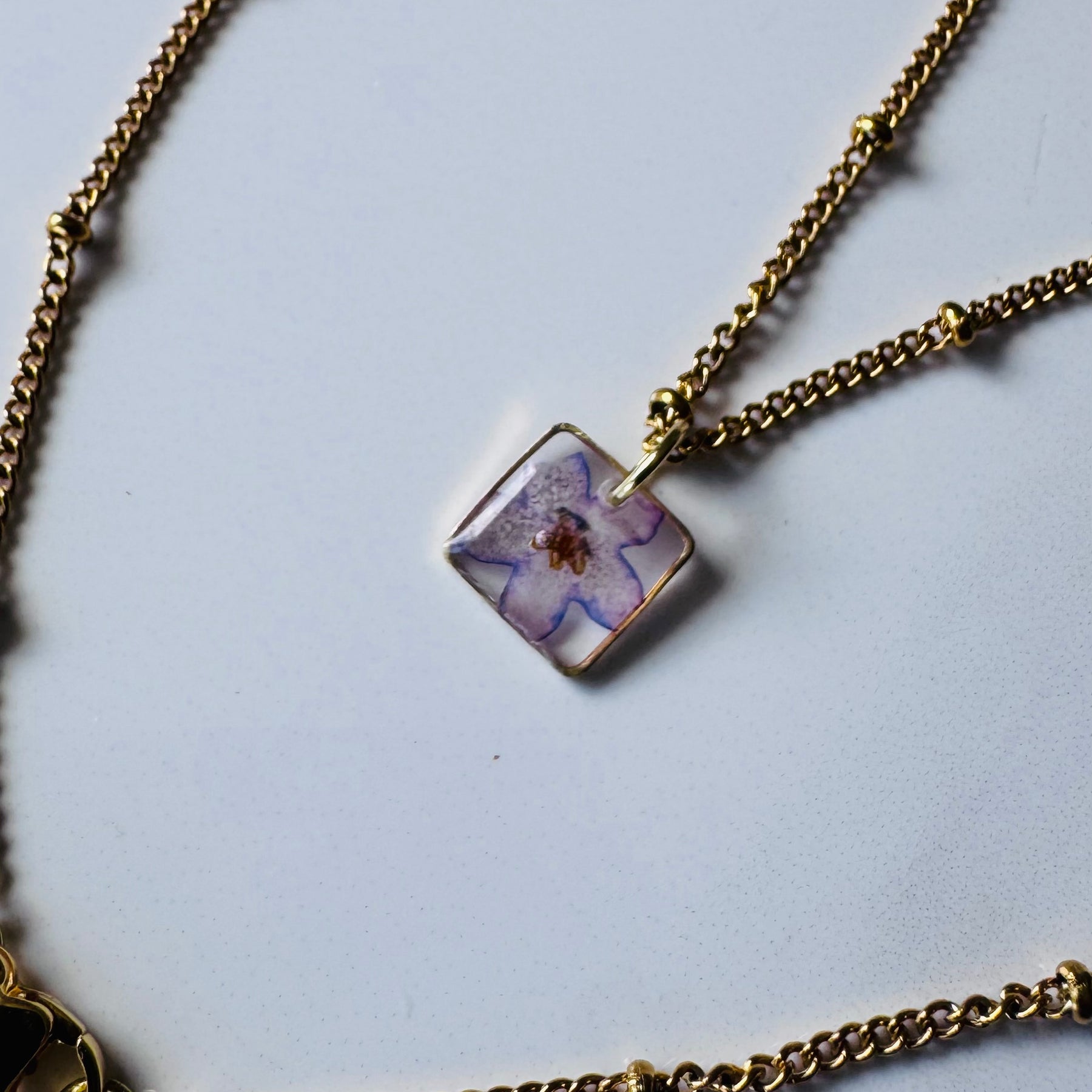 Gold plated resin necklace with purple wildflower