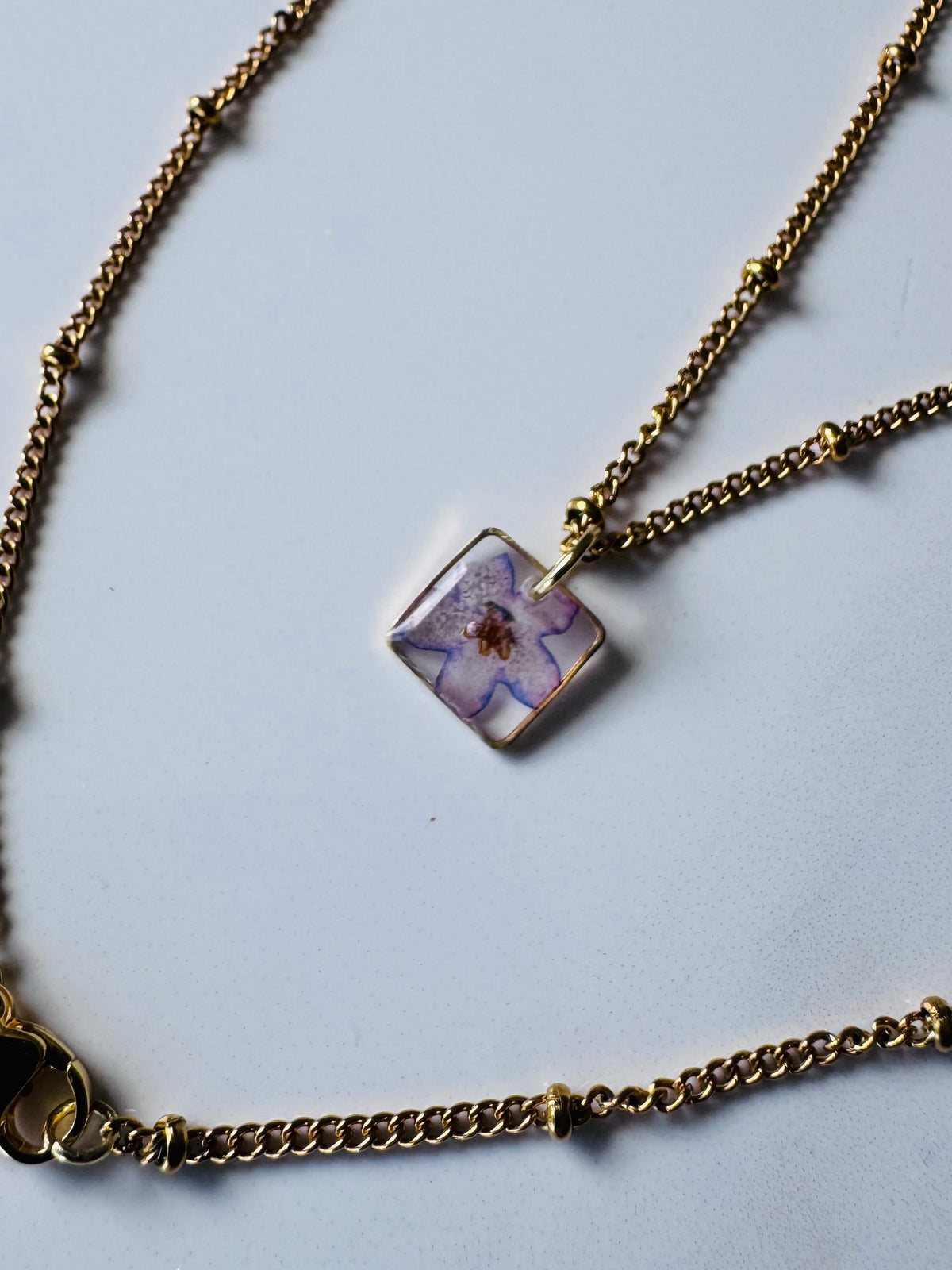 Gold plated resin necklace with purple wildflower