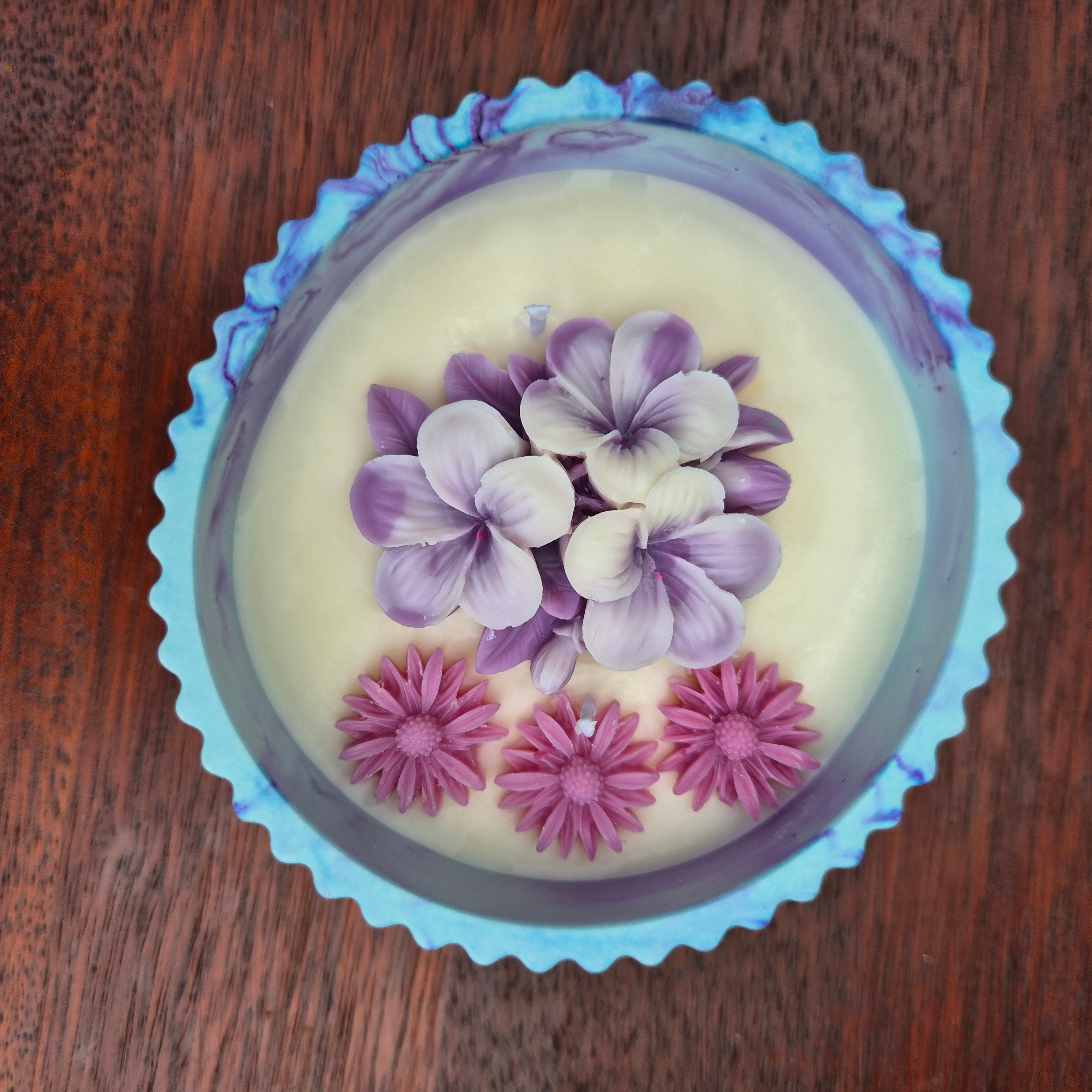 Round blue and purple concrete bowl candle with frangipani flower