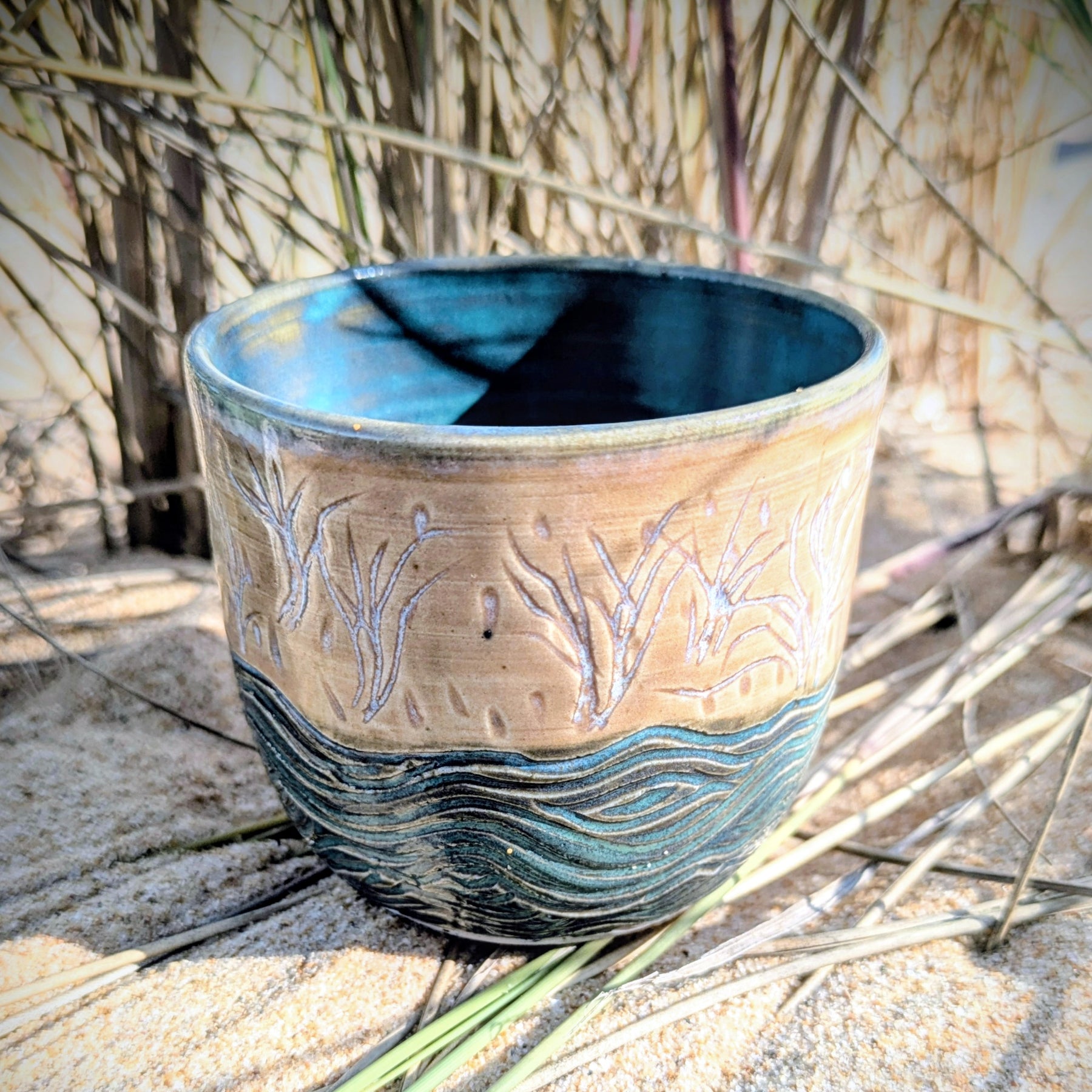 Sand dunes reeds and water tumbler