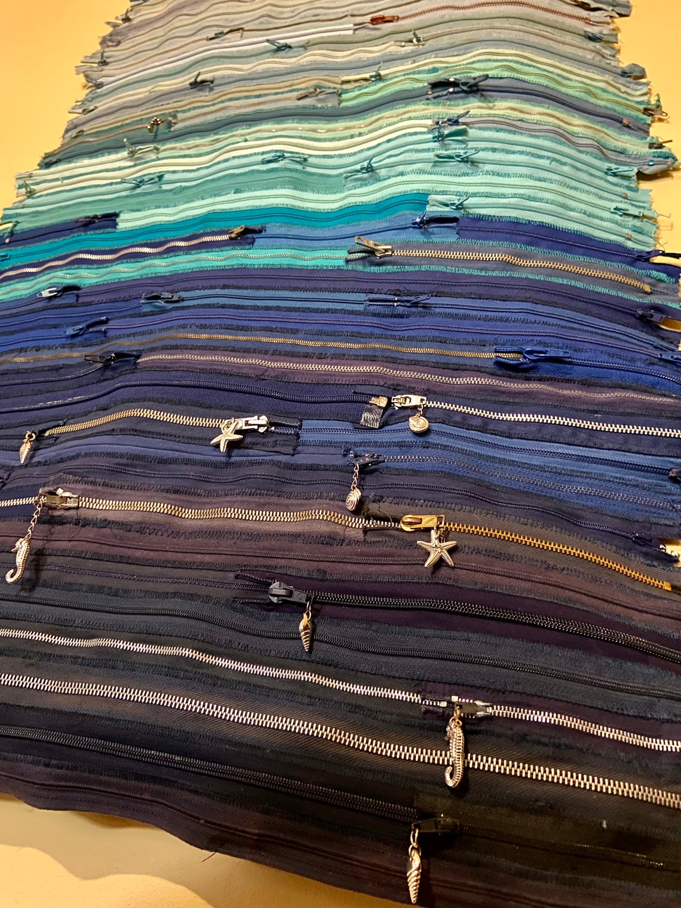 Upcycled 90 zips textile wall hanging. Ocean & Sky theme. Adorned with charms. Blue colour scheme. Ready to hang includes 2 x dowel rods