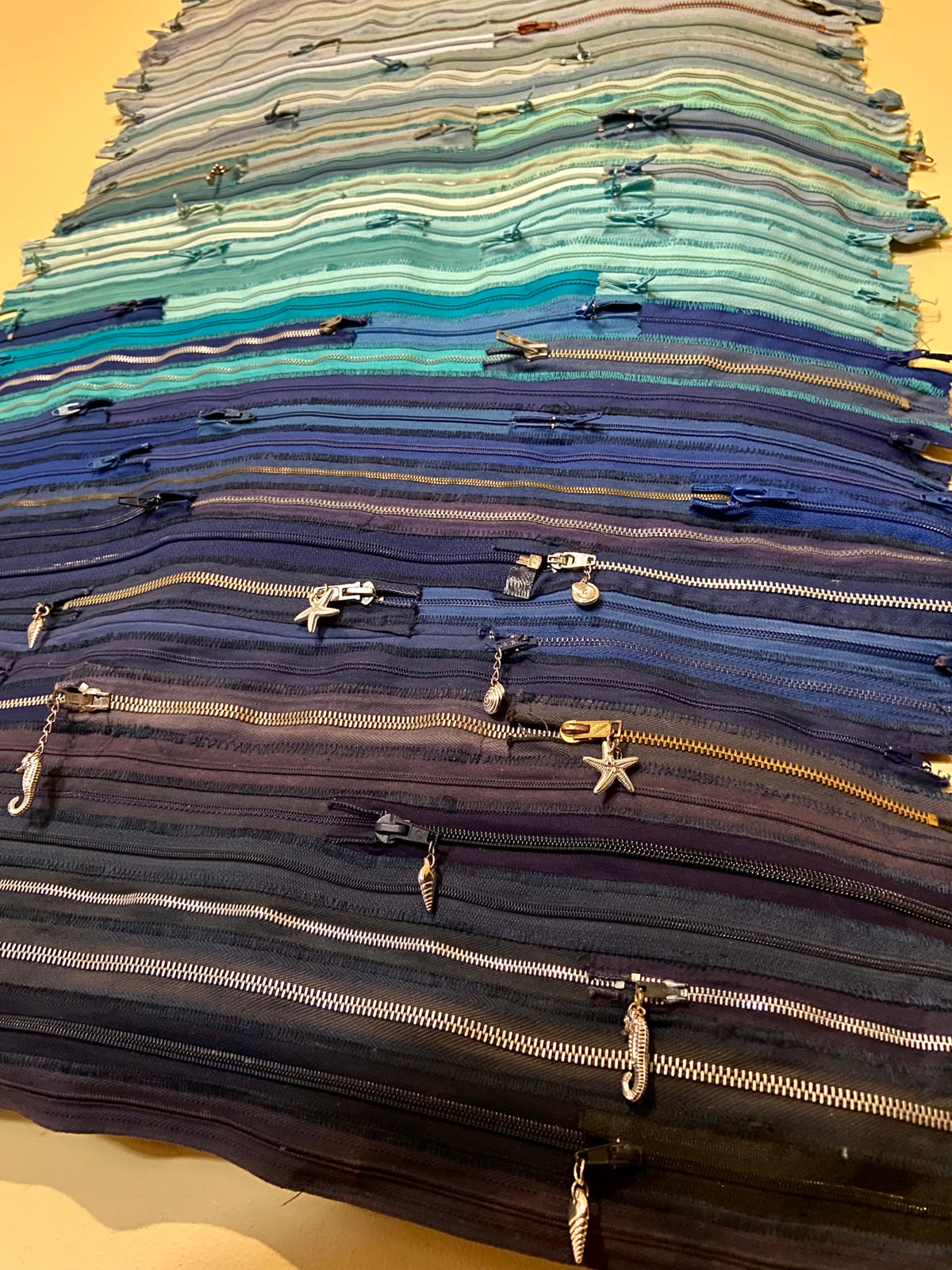 Upcycled 90 zips textile wall hanging. Ocean & Sky theme. Adorned with charms. Blue colour scheme. Ready to hang includes 2 x dowel rods