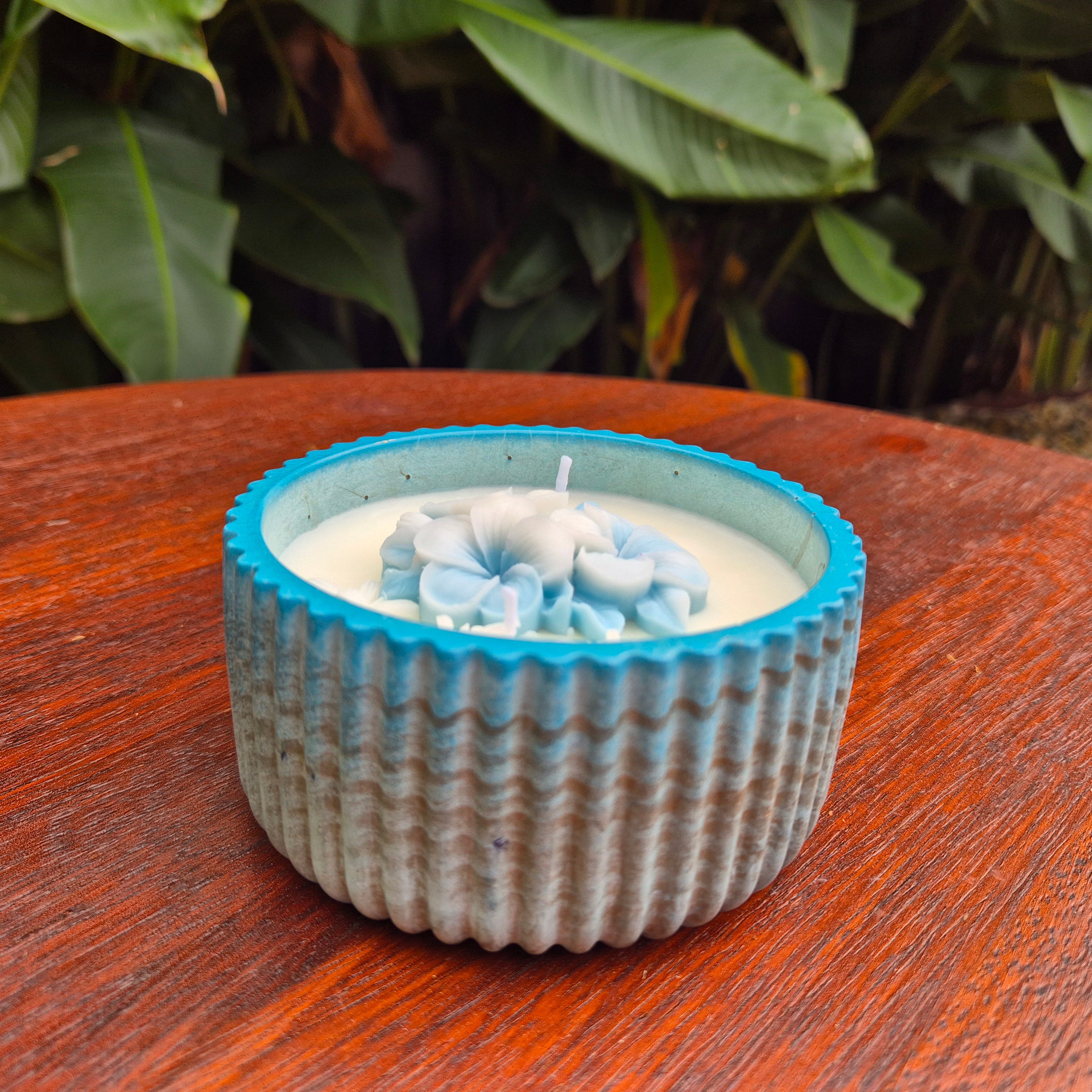 Round blue and gold concrete bowl candle with frangipani flower