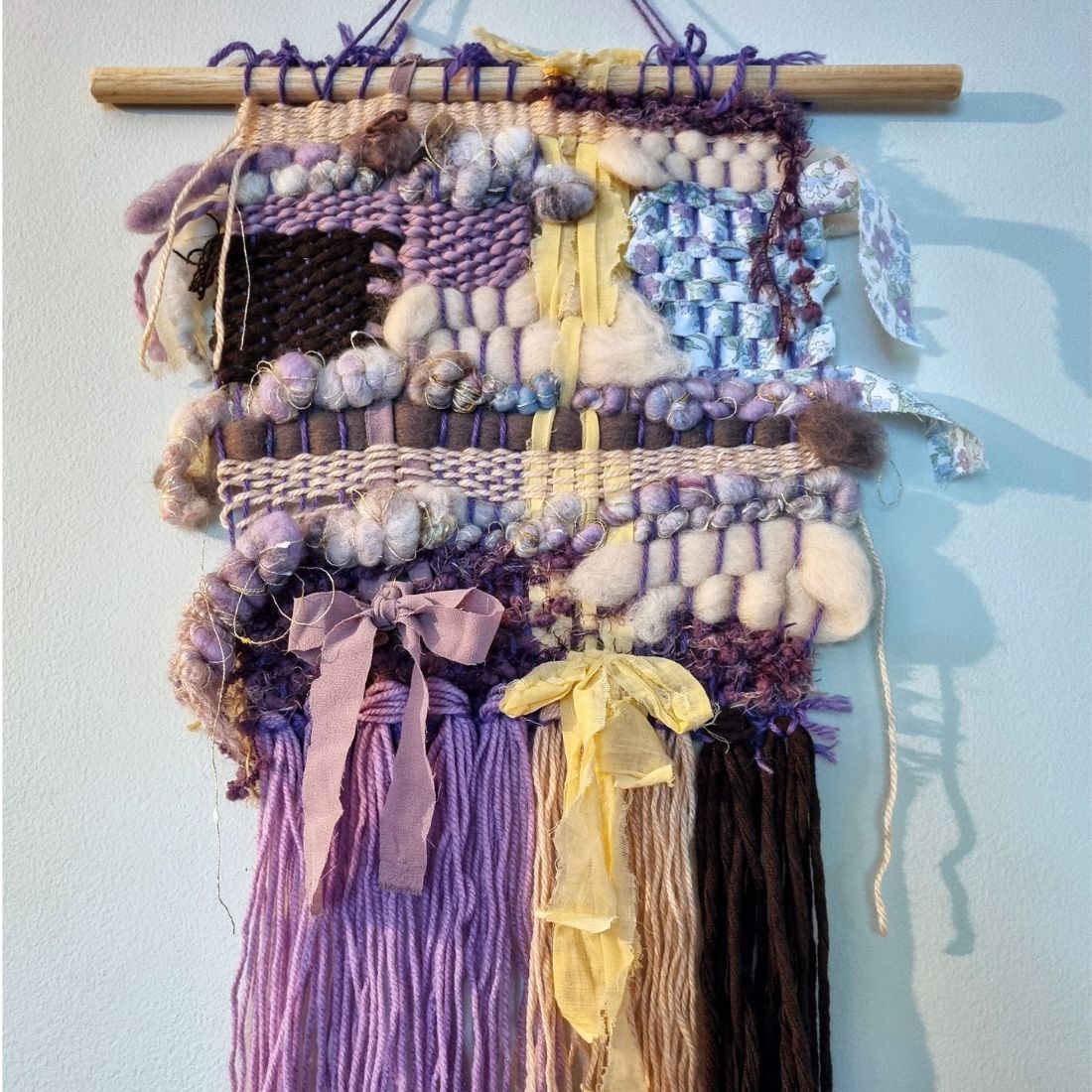 Handwoven textured wall hanging in purple, yellow and brown