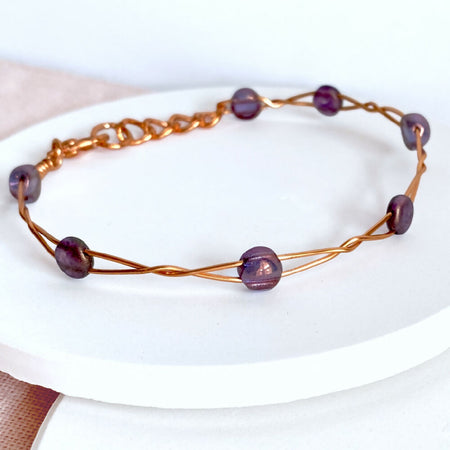 Twisting copper wire bracelet with shimmer purple glass beads