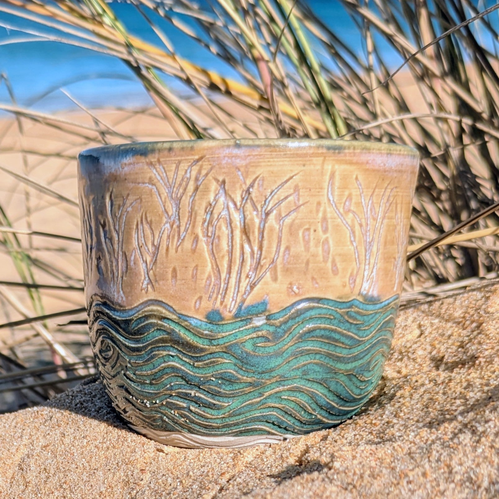 Sand dunes reeds and water tumbler