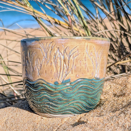 Sand dunes reeds and water tumbler