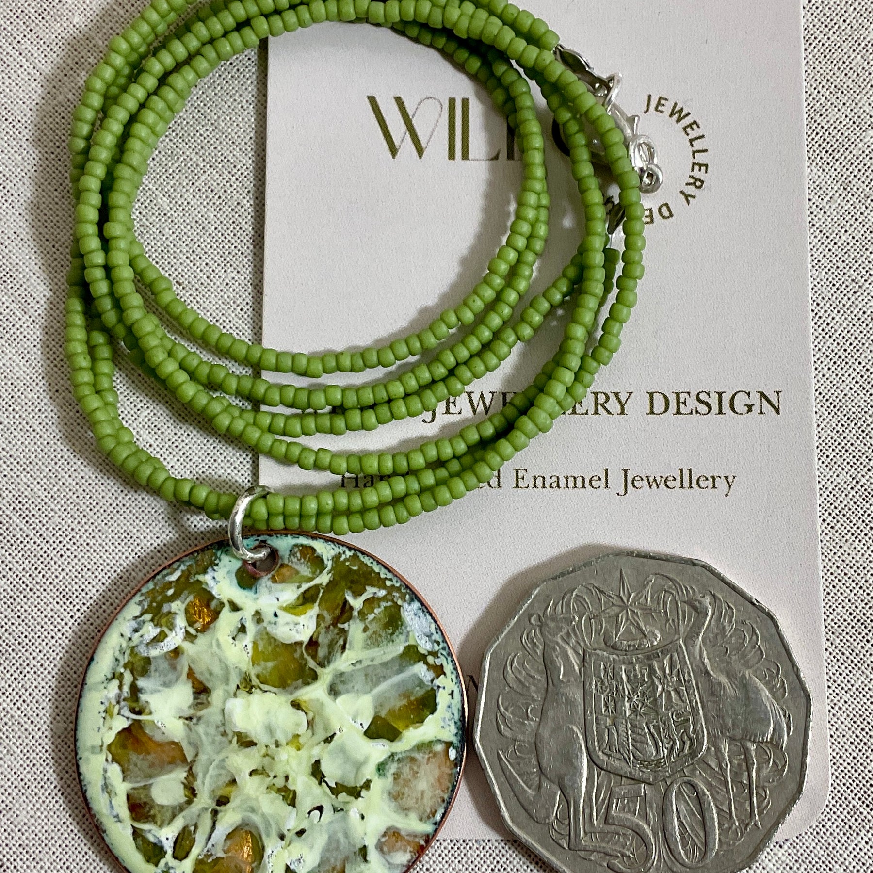 Yellow and green enamel pendant on green seed beads.