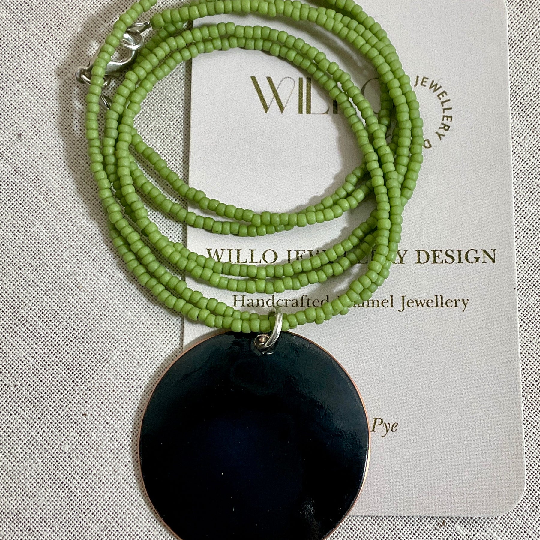 Yellow and green enamel pendant on green seed beads.