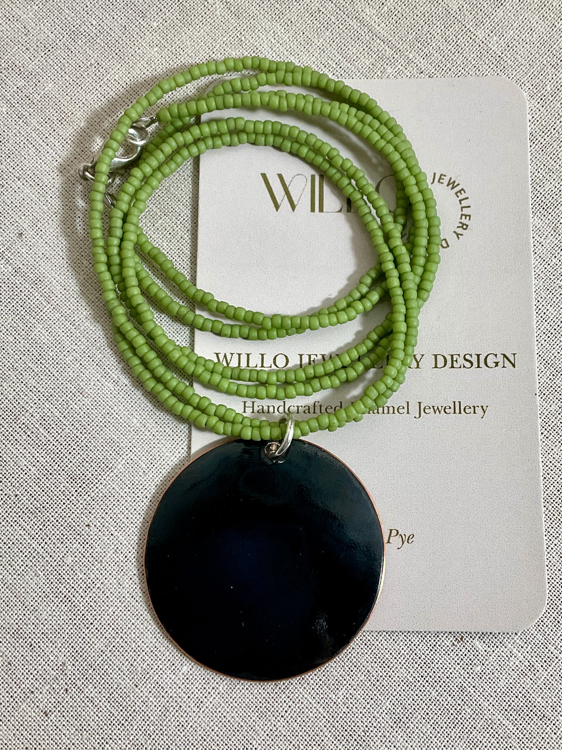 Yellow and green enamel pendant on green seed beads.