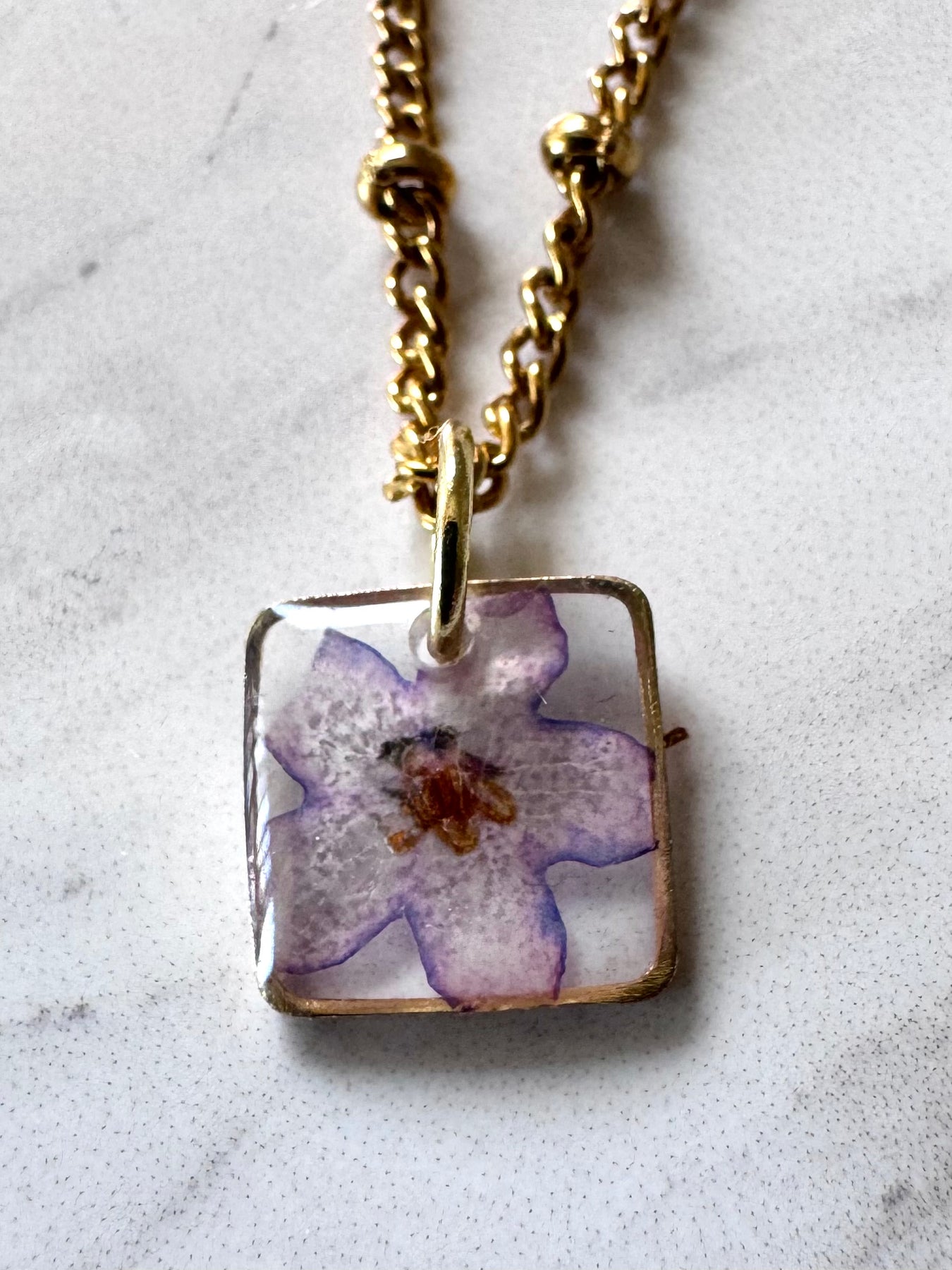Gold plated resin necklace with purple wildflower