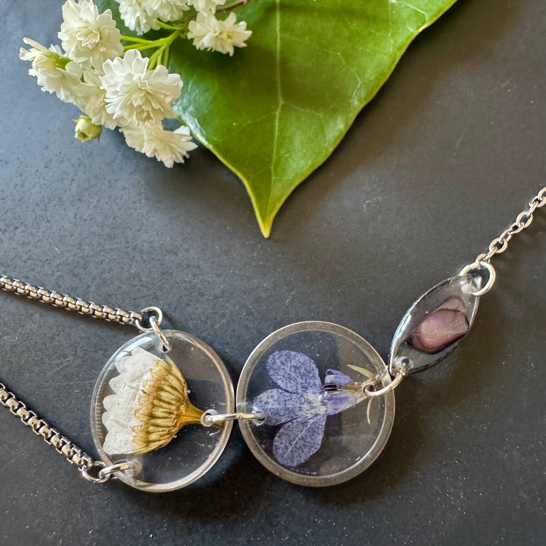 Botanical resin hand chain in silver with pressed flowers and cowrie shell