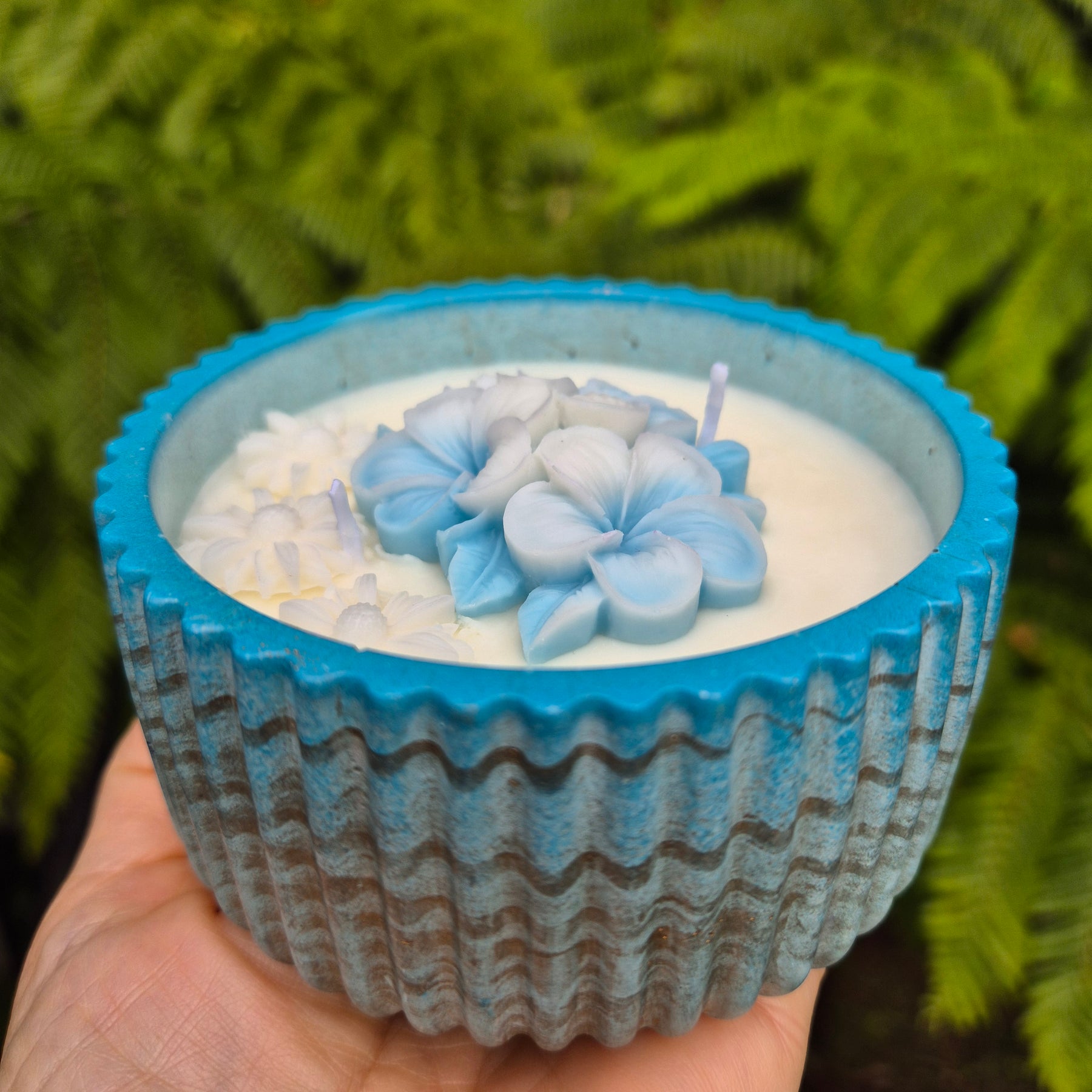 Round blue and gold concrete bowl candle with frangipani flower