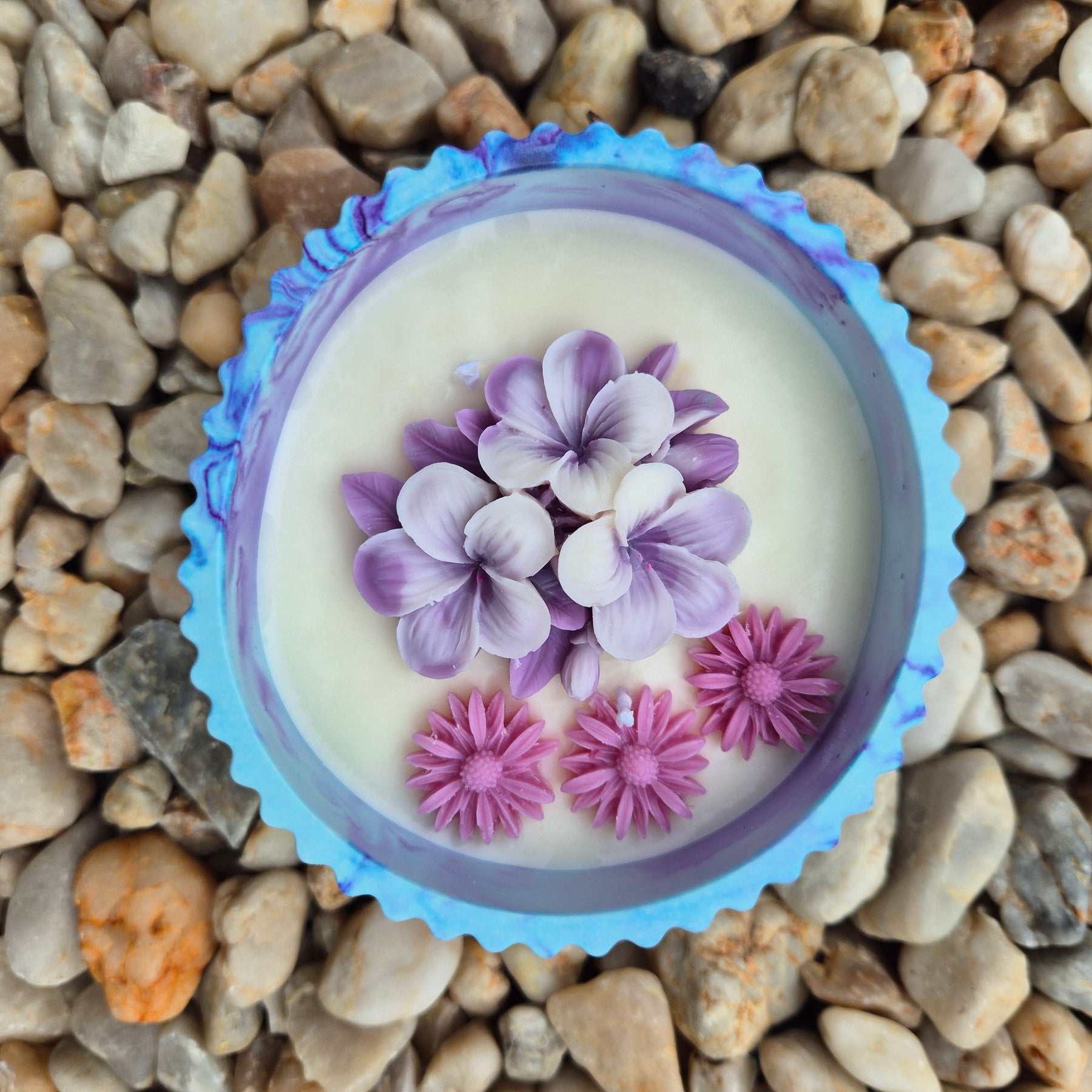 Round blue and purple concrete bowl candle with frangipani flower