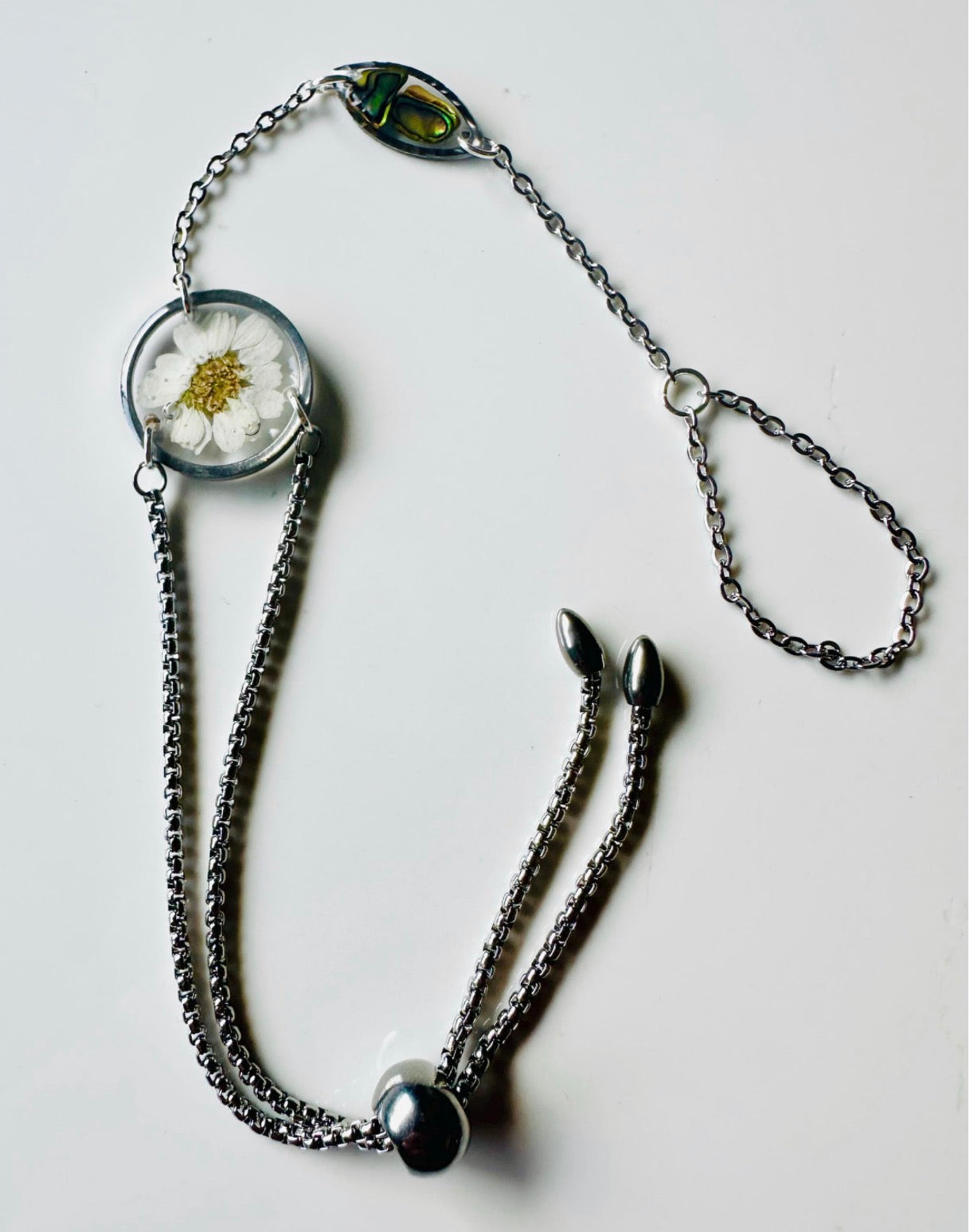 Botanical resin hand chain in silver with pressed flowers and cowrie shell