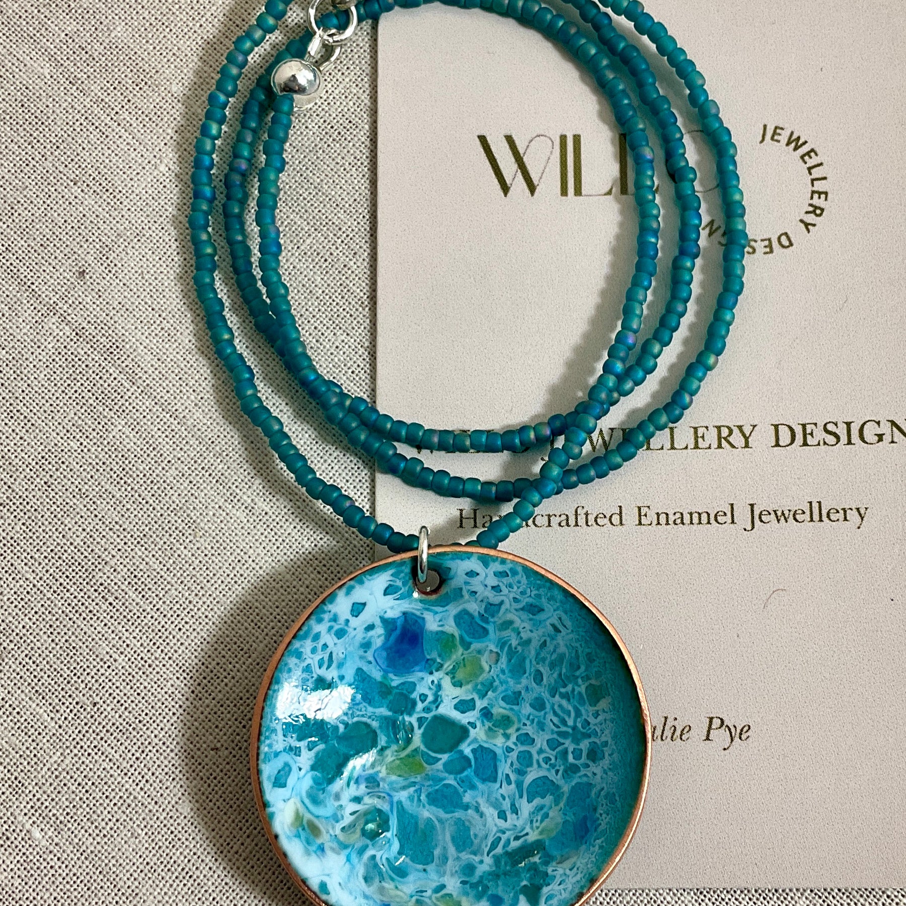 Blue and green enamel pendant on glass seed beads