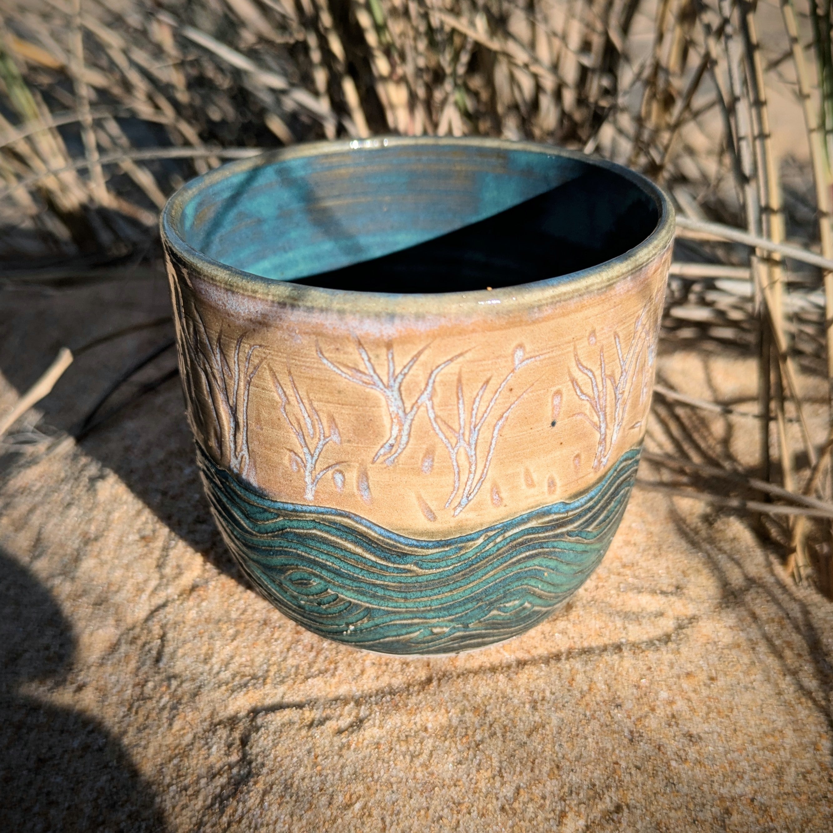 Sand dunes reeds and water tumbler