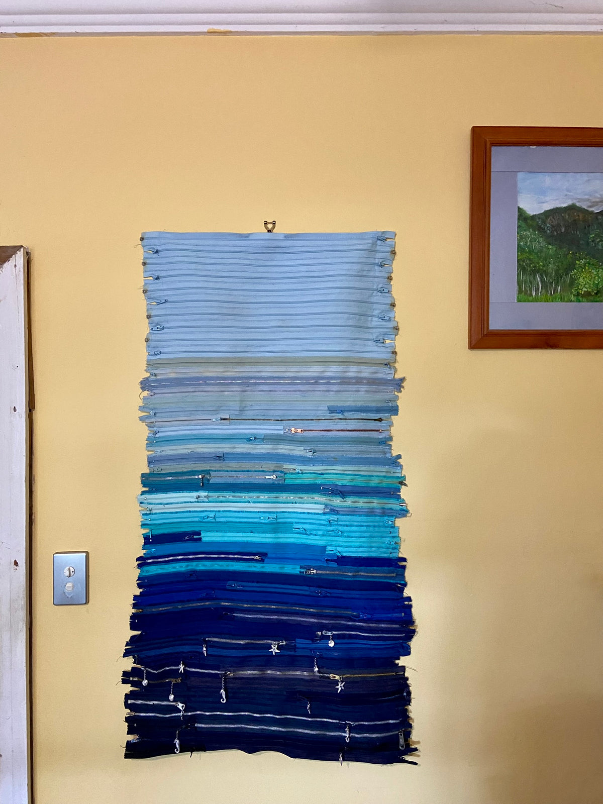 Upcycled 90 zips textile wall hanging. Ocean & Sky theme. Adorned with charms. Blue colour scheme. Ready to hang includes 2 x dowel rods
