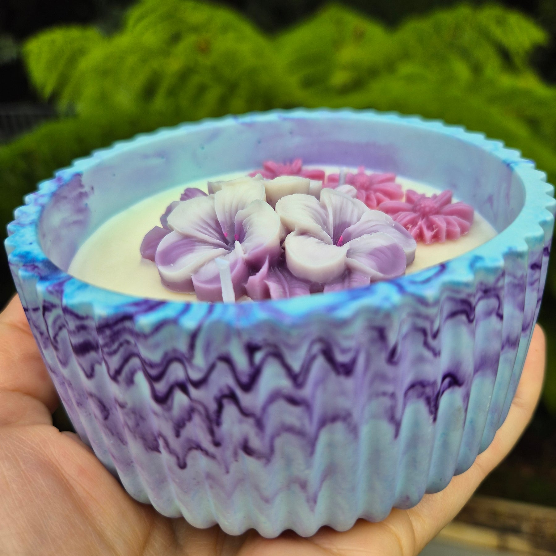 Round blue and purple concrete bowl candle with frangipani flower