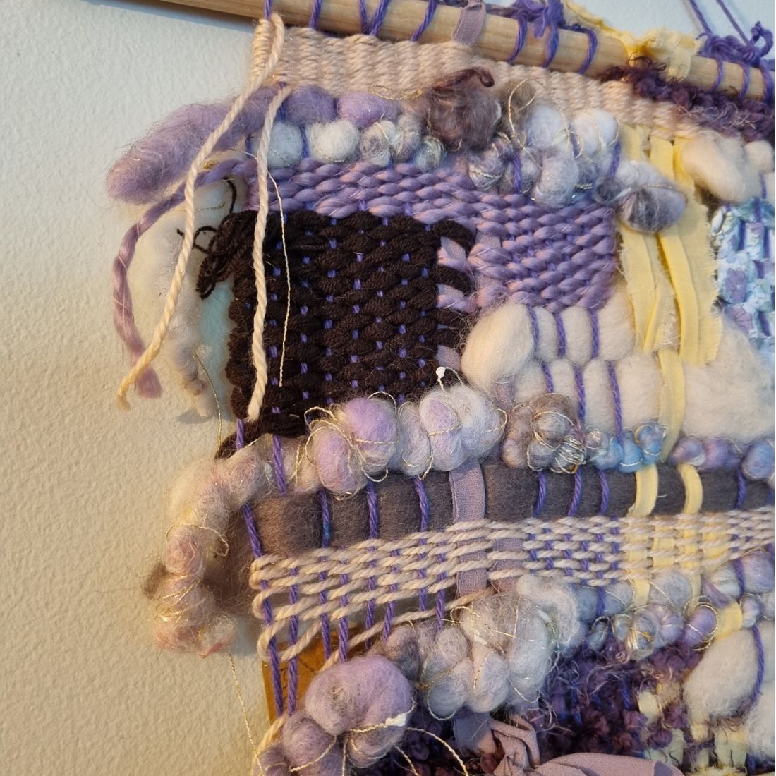 Handwoven textured wall hanging in purple, yellow and brown