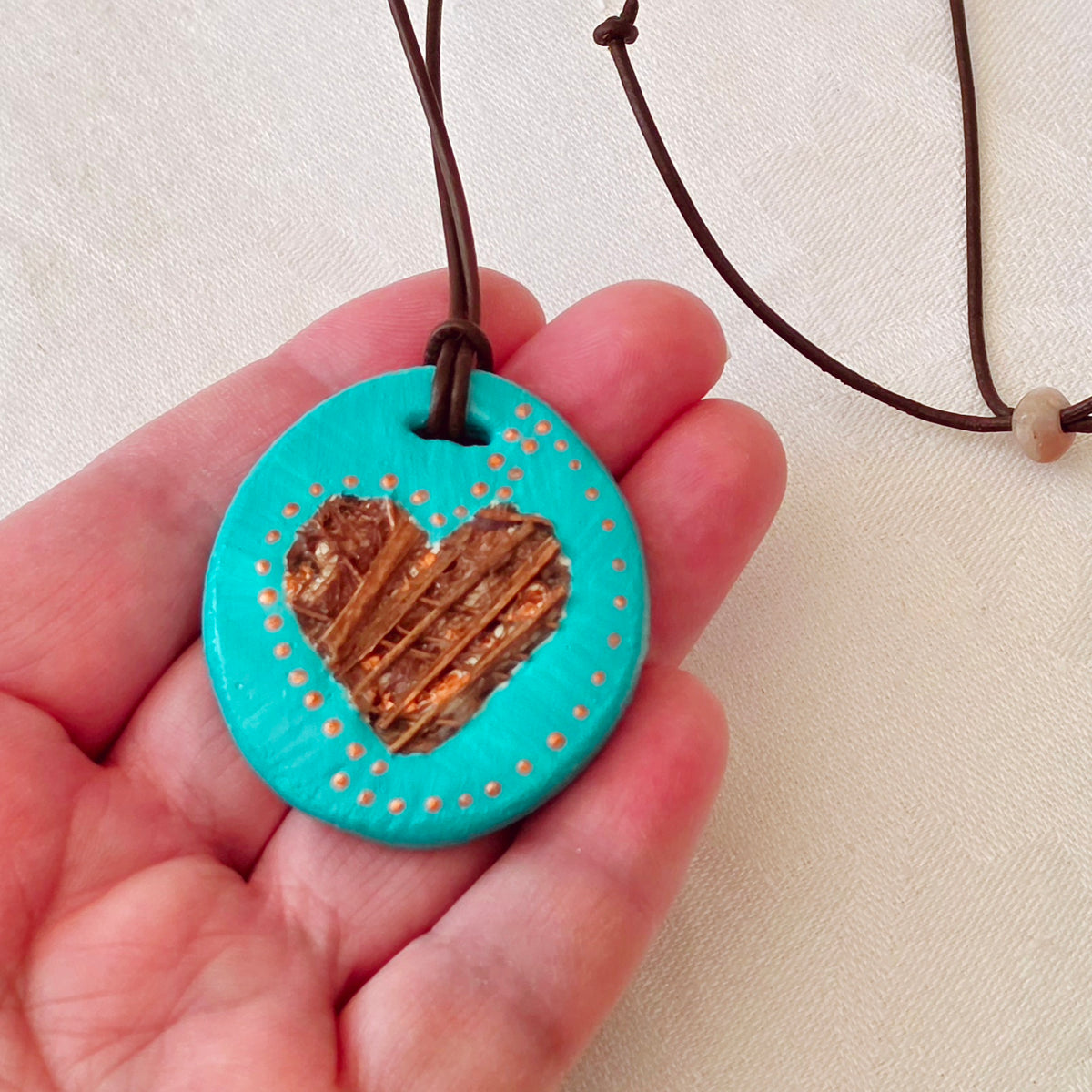 Hand-painted natural clay pendant with palm fibre heart