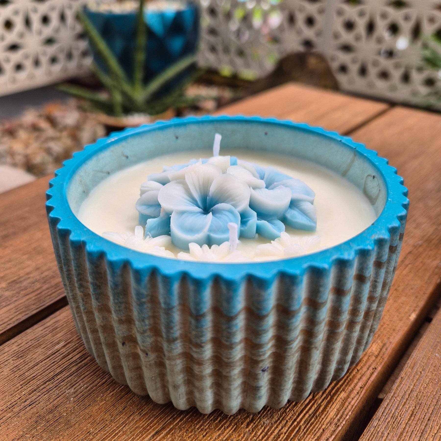 Round blue and gold concrete bowl candle with frangipani flower