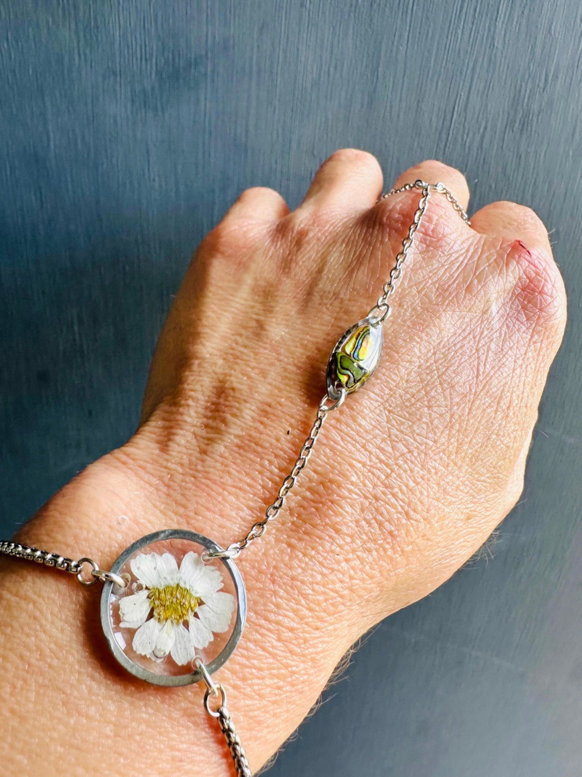 Botanical resin hand chain in silver with pressed flowers and cowrie shell