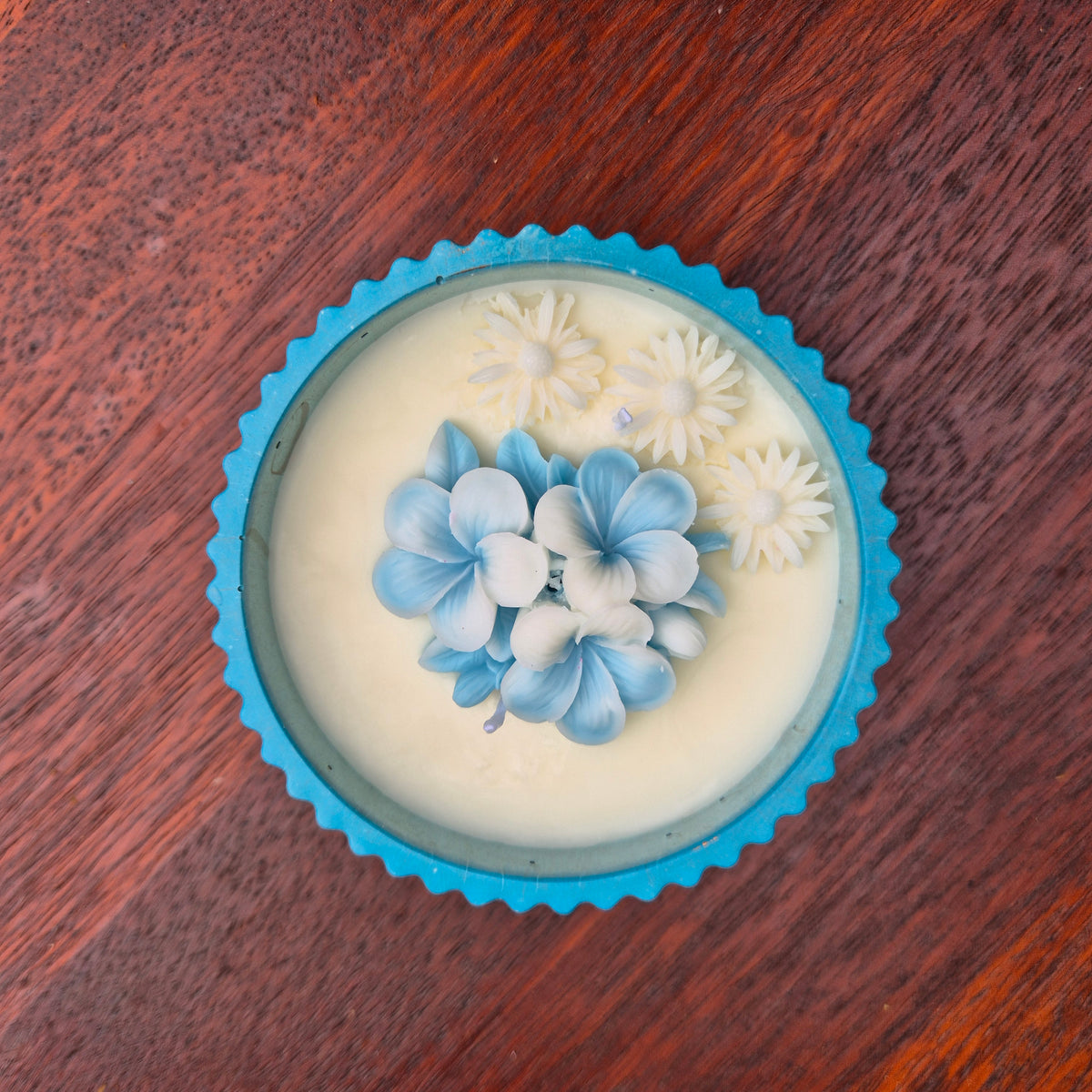 Round blue and gold concrete bowl candle with frangipani flower